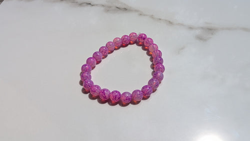Fushcia beaded stretch bracelet laid out flat on whit marbled tile 
