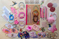 A flat-lay display of various handmade beaded bracelets, keychains, magnetic bookmarks, stickers, stationary items suck as pens, pencils, a notebook, and small craft accessories arranged on a light wood surface.