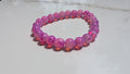 Fushcia beaded stretch bracelet laid out flat on white marbled tile