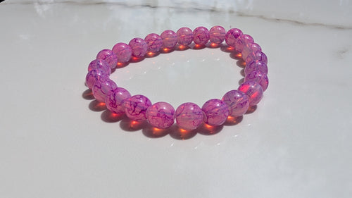 Fushcia beaded stretch bracelet laid out flat on white marbled tile